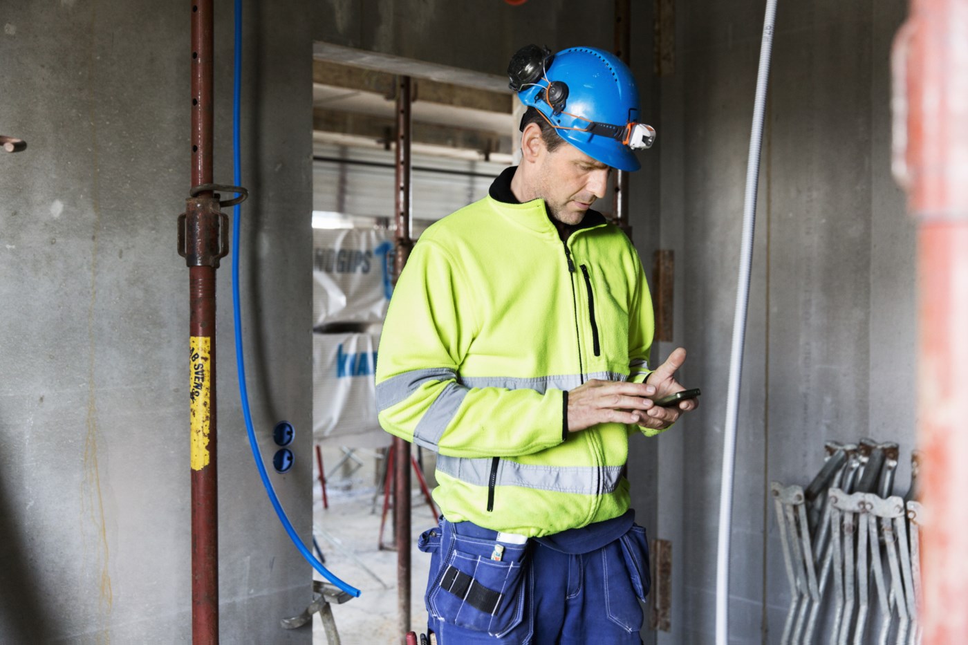 Bygningsarbeider ser på mobilen.