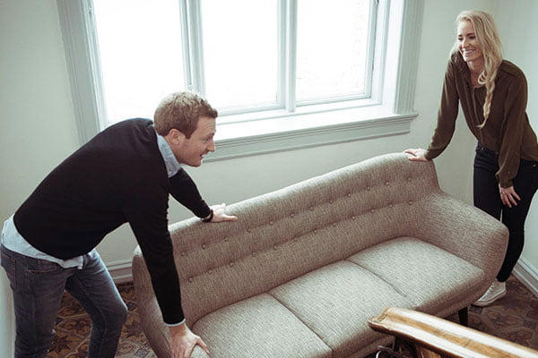 Ungt par flytter en sofa i trapp. Foto