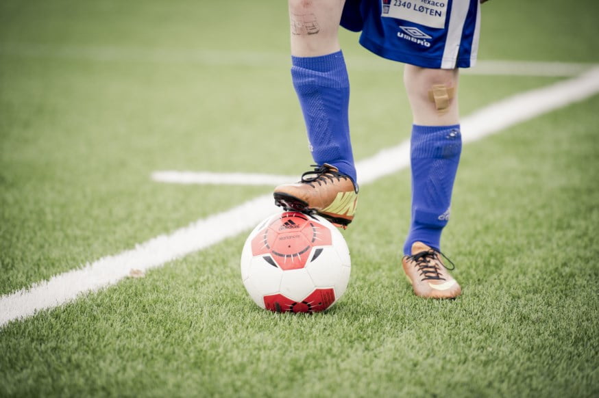 Gutt med fotballdrakt med foten på ballen. foto